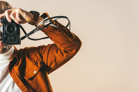 partial view of man taking picture on photo camera isolated on beige