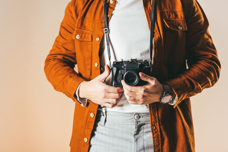 partial view of man in fashionable clothing with photo camera isolated on beigeの写真素材
