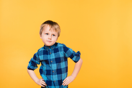 portrait of little boy in shirt standing akimbo isolated on yellowの写真素材