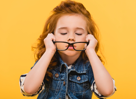 portrait of cute little kid wearing eyeglasses isolated on yellowの写真素材