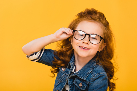 portrait of cute smiling kid in eyeglasses isolated on yellowの写真素材
