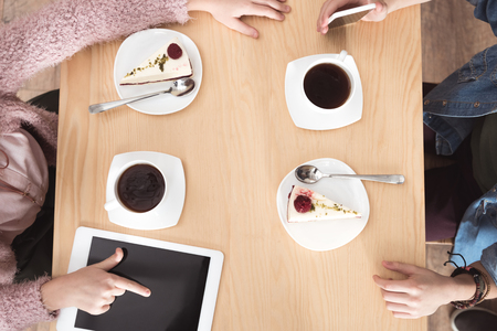cropped image of children sitting at table with gadgets on surface at cafeの写真素材