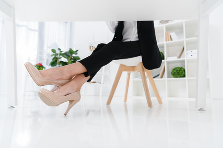 partial view of businesswoman sitting at workplace in officeの写真素材