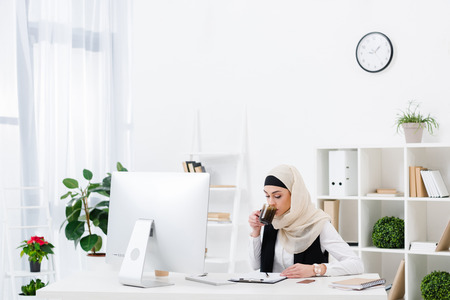 portrait of arabic businesswoman drinking coffee at workplace in officeの写真素材