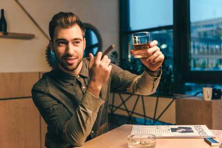 portrait of businessman with cigar holding glass of cognac in cafeの写真素材