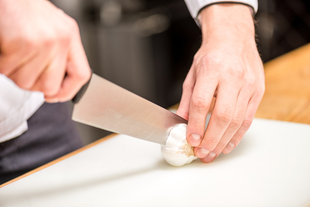 cropped image of chef cutting garlicの写真素材