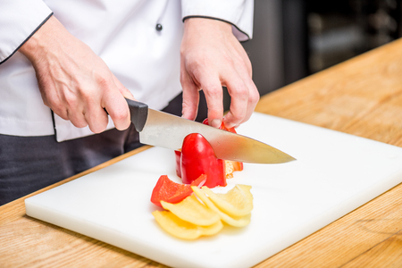 cropped image of chef cutting red and yellow bell peppersの写真素材