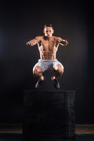 athletic young sportsman jumping from block on blackの写真素材