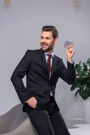 smiling businessman throwing paper plane in officeの写真素材