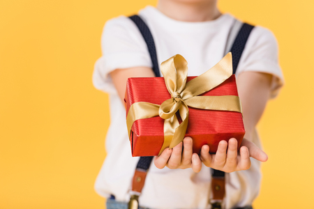 cropped shot of kid holding wrapped gift isolated on yellow, mothers day conceptの写真素材