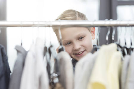 smiling caucasian boy looking on clothes at storeの写真素材