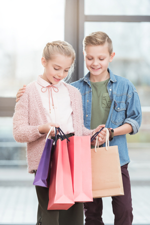two happy kids looking down on paper bags at shopの写真素材