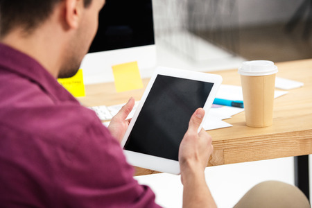 partial view of businessman using tablet with blank screen at workplace in officeの写真素材