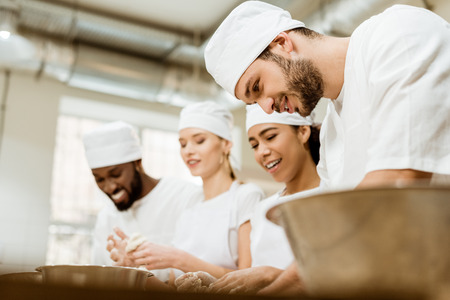 group of happy baking manufacture workers kneading dough togetherの写真素材