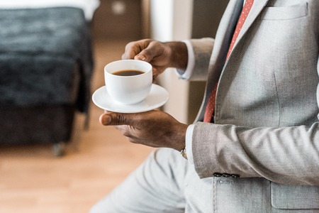 cropped view of elegant african american man holding cup of coffeeの写真素材