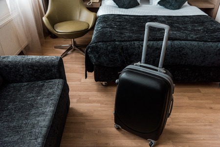black suitcase for travel in hotel room with bed and armchairの写真素材