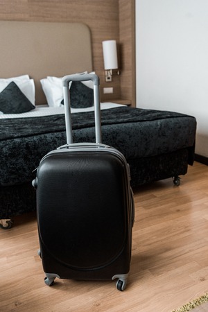 black travel bag in hotel room with bedの写真素材