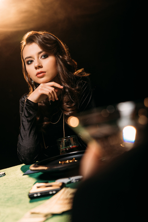attractive pensive girl looking away at poker table in casinoの写真素材