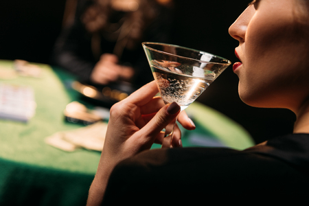 cropped image of girl drinking cocktail while playing poker at table in casinoの写真素材