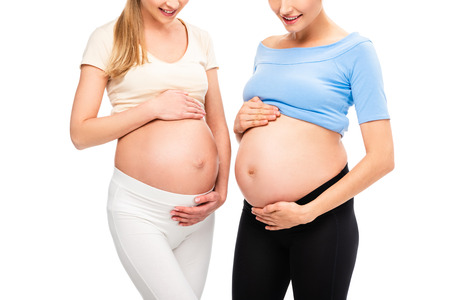 cropped view of two pregnant women showing bellies isolated on whiteの写真素材