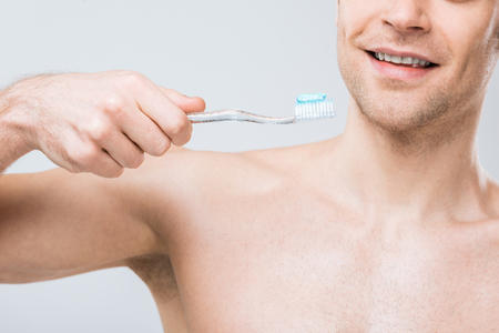 cropped view of man holding toothbrush with toothpaste, isolated on greyの写真素材