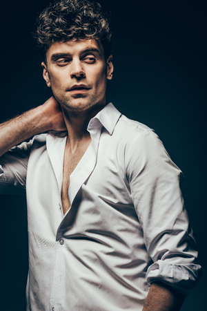 handsome man posing in white shirt isolated on dark greyの写真素材