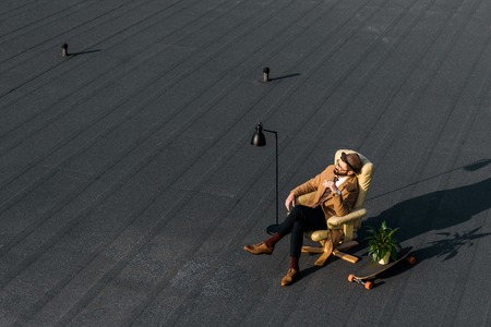 adult businessman resting in armchair with cigarette on roofの写真素材