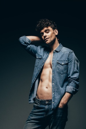 sexy macho posing in denim clothes isolated on dark greyの写真素材