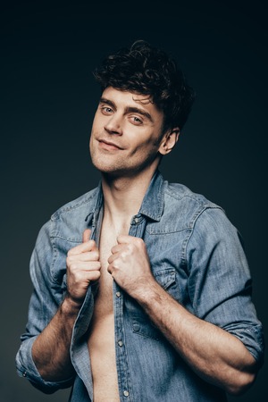 handsome smiling man posing in jeans clothes isolated on dark greyの写真素材