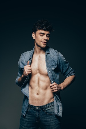 sexy macho posing in jeans clothes isolated on dark greyの写真素材