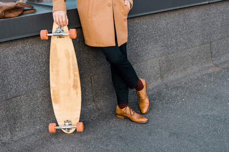 cropped view of businessman in coat holding penny boardの写真素材