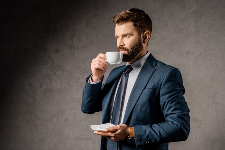 handsome businessman drinking coffee and holding saucerの写真素材
