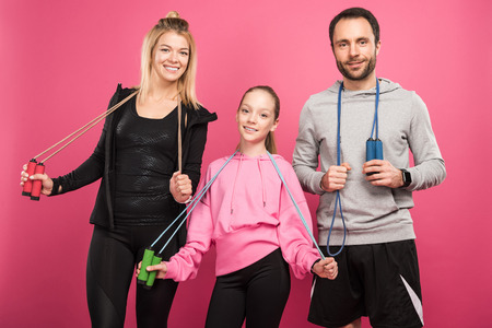 athletic family holding jump ropes, isolated on pinkの写真素材