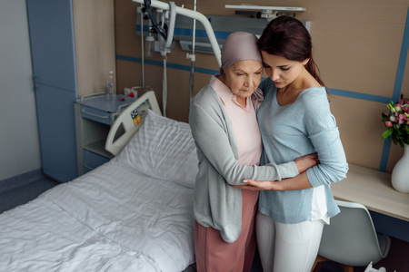 upset daughter embracing sick senior mother with cancer in hospitalの写真素材