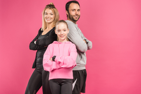 athletic family posing in sportswear with crossed arms, isolated on pinkの写真素材