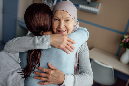 happy senior woman in kerchief embracing daughter in hospitalの写真素材
