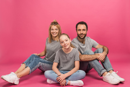 beautiful family with happy daughter sitting on pinkの写真素材