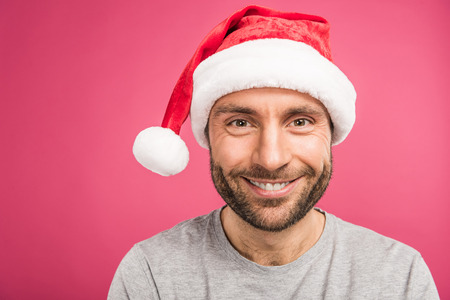 portrait of handsome smiling man in santa hat, isolated on pinkの写真素材