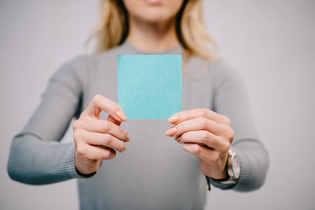 cropped view of woman holding blue empty paper note isolated on greyの写真素材