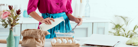Cropped view of pin up girl adding milk from bottle to the ingredients for making dough