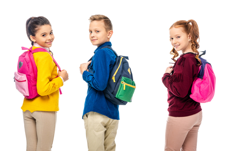 schoolchildren with multicolored backpacks smiling at camera isolated on whiteの写真素材