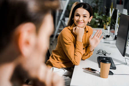 smiling businesswoman greeting colleague at workplace in officeの写真素材