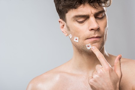 handsome man touching face after bad shaving, isolated on greyの写真素材