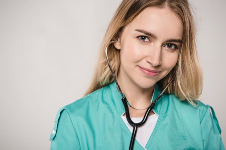 attractive female doctor with stethoscope in ears  isolated on greyの写真素材