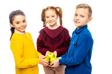 smiling kids holding apples and looking at camera isolated on whiteの写真素材