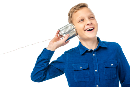 smiling boy holding tin with rope near ear isolated on whiteの写真素材