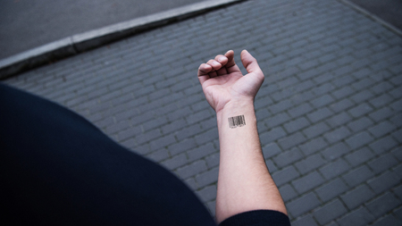 cropped view of man with barcode on hand with bricks on backgroundの写真素材
