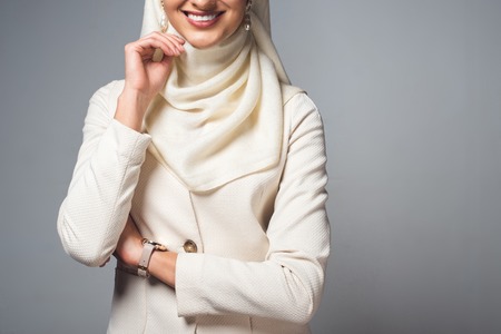 cropped shot of smiling young muslim woman standing isolated on greyの写真素材