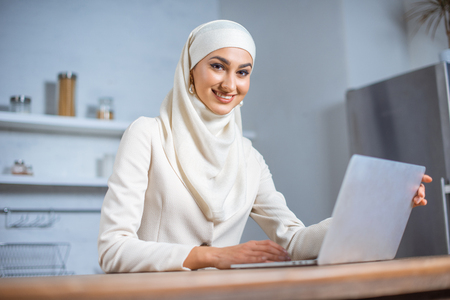 beautiful young muslim woman using laptop and smiling at cameraの写真素材