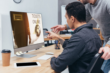 cropped shot of business colleagues using desktop computer with tickets online website on screen in officeの写真素材